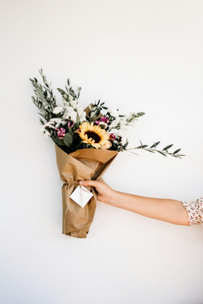 Seasonal hand-tied bouquet held against a warm neutral background
